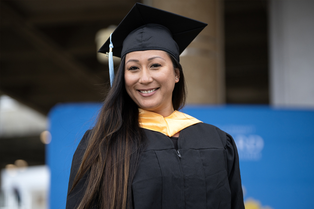 Leeward student at commencement ceremony, smiling for camera