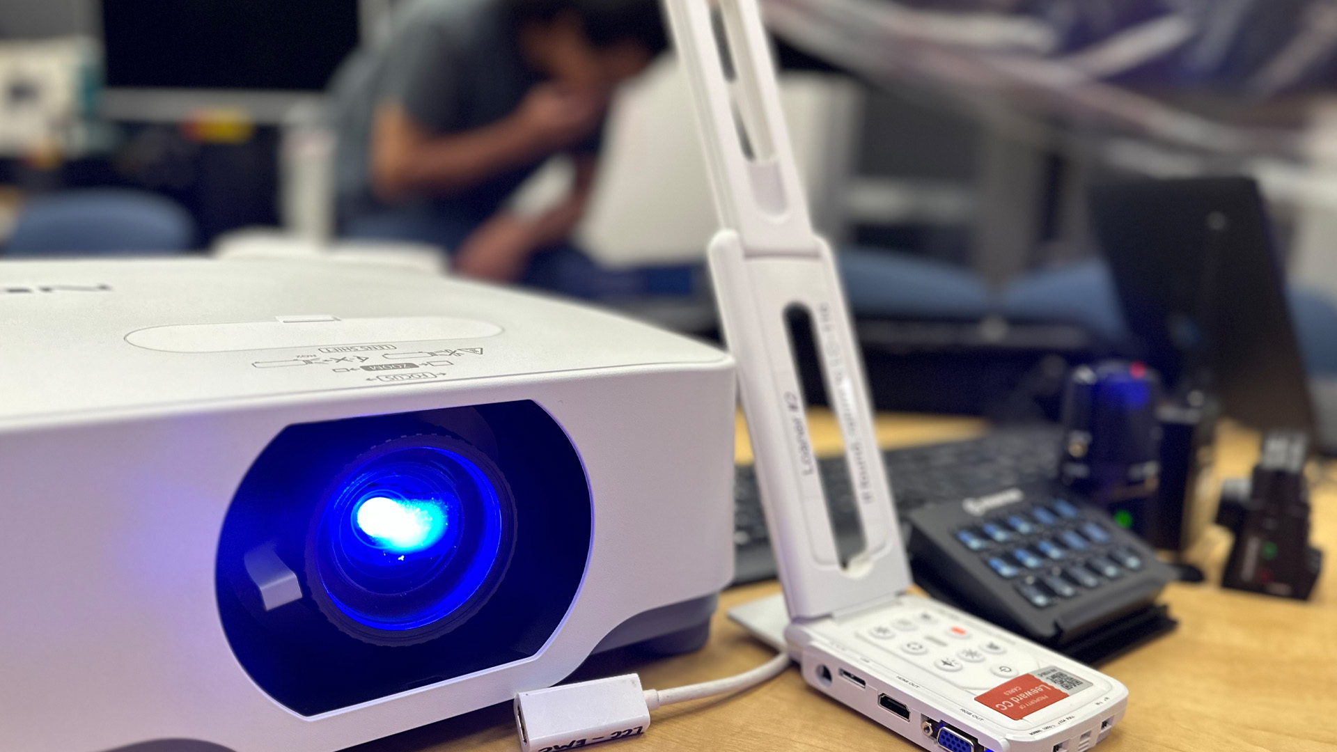 AV equipment – projector, microphone, webcam, displayed on table.